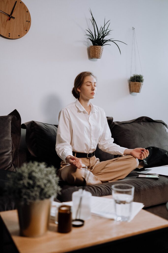 fiatal nő a nappalijában a kanapén meditációt, mindfulness technikát gyakorol